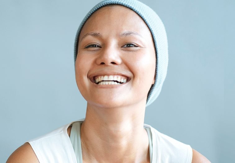 Portrait of the patient's smile is a cancer asian, where the strong mind is treated with chemo behind a gray wall.